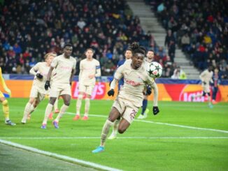 Joueur de football poursuivant le ballon sur le terrain.