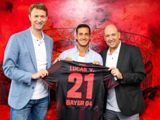 Trois hommes tiennent un maillot de football.
