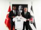 Deux hommes tenant un maillot de football Besiktas.
