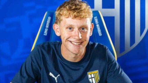 Homme souriant en maillot de football, fond bleu.