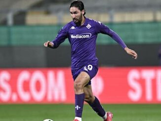 Footballeur en action sur le terrain, maillot violet.