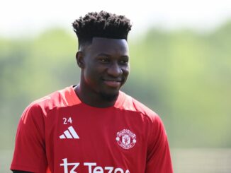 Joueur de football en maillot rouge souriant.