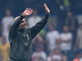 Homme saluant la foule lors d'un événement sportif.