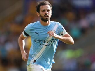 Footballeur en action sur le terrain, maillot bleu.