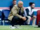 Homme accroupi sur un terrain de football.