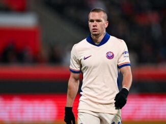 Joueur de football en tenue blanche sur le terrain.