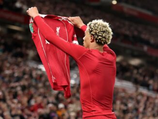 Footballeur soulevant maillot devant la foule en liesse.