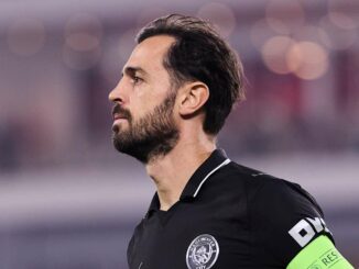 Joueur de football en tenue noire, profil gauche.