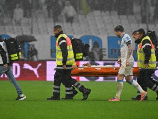 Joueur blessé évacué sur une civière sous la pluie.