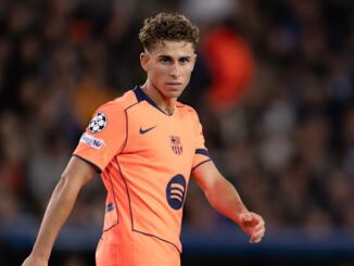 Joueur de football en maillot orange sur le terrain.