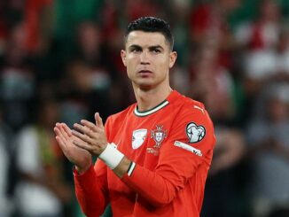 Joueur de football applaudissant en maillot rouge.