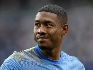 Homme souriant en maillot de sport bleu.