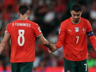 Deux footballeurs en maillots rouges sur le terrain.