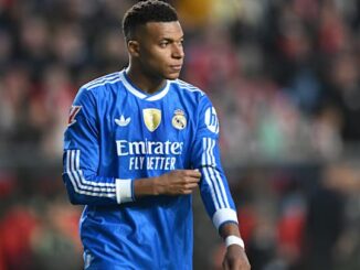 Joueur en maillot de football bleu sur le terrain.