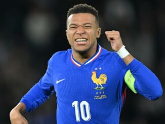 Joueur de football en maillot bleu célébrant.