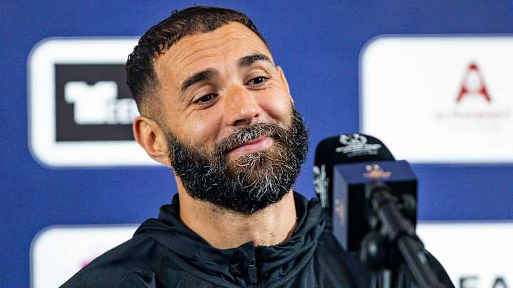 Homme souriant lors d'une conférence de presse sportive.