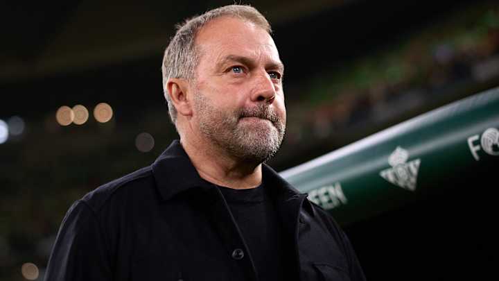Homme barbu en manteau noir, regard sérieux.