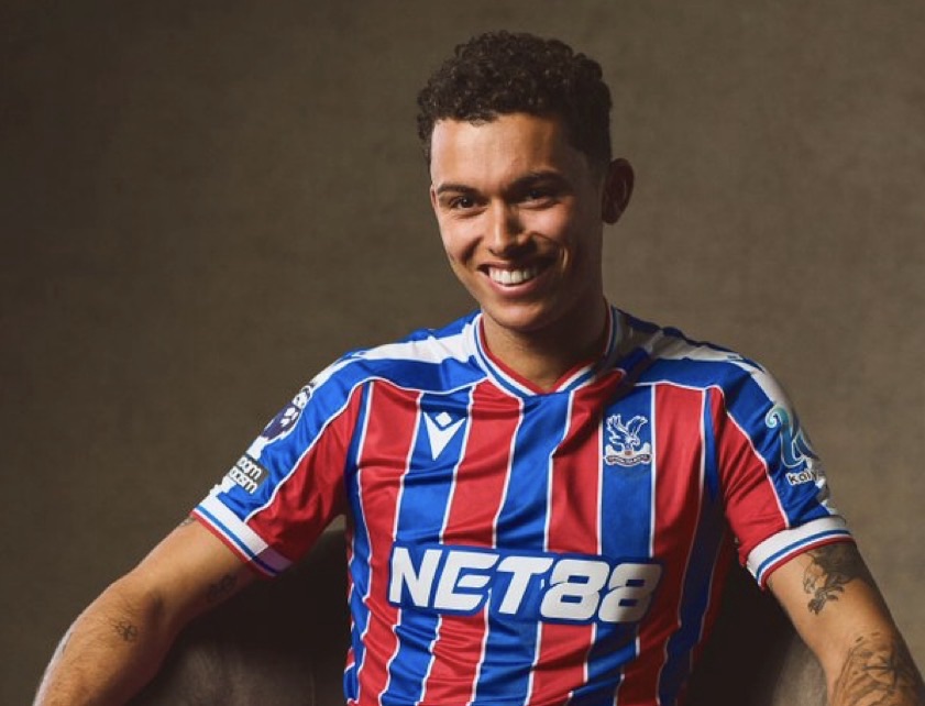 Homme souriant portant un maillot de football à rayures.