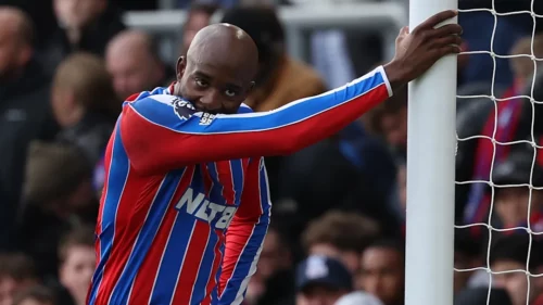 Footballeur en tenue rayée rouge et bleue au poteau.