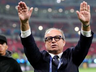 Homme en costume levant les bras dans un stade