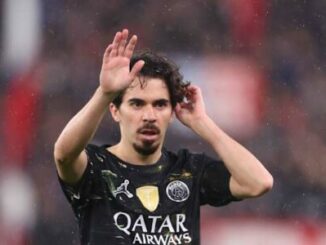 Footballeur levant la main sous la pluie