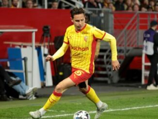 Footballeur en maillot jaune et rouge frappant le ballon