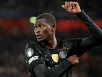 Footballeur en maillot noir levant le bras