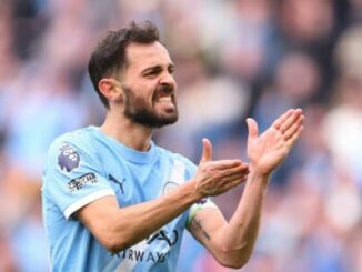 Footballeur en maillot bleu applaudissant sur le terrain