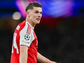 Footballeur en maillot rouge et blanc sur terrain