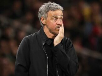 Homme pensif au bord d’un terrain de football