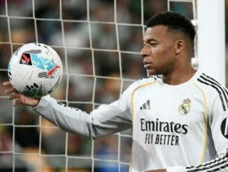 Footballeur en maillot blanc tenant un ballon