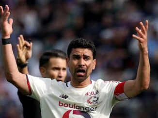 Footballeur levant les bras en signe de protestation