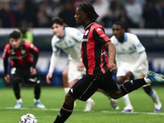 Footballeur en noir et rouge frappant le ballon