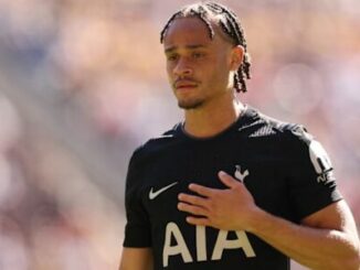 Footballeur en maillot noir, main sur la poitrine