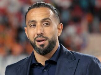 Homme barbu en costume dans un stade