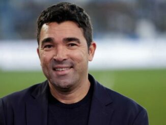 Homme souriant en veste sombre, fond flou extérieur