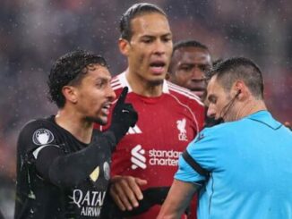 Joueurs de football protestant auprès de l’arbitre sous la pluie