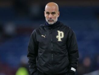 Entraîneur de football en veste noire au stade