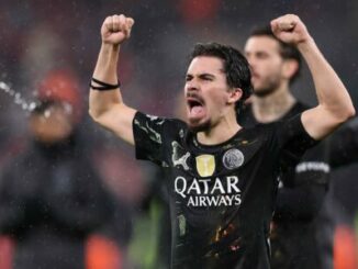 Footballeur en maillot noir célébrant sous la pluie