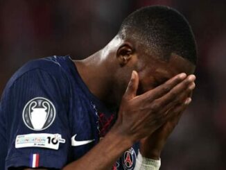 Footballeur en maillot bleu se tenant le visage