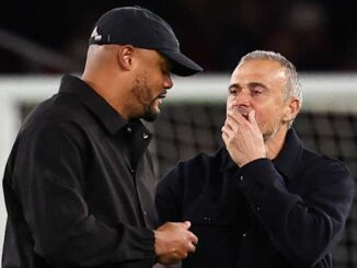 Deux hommes discutant au bord d’un terrain de football