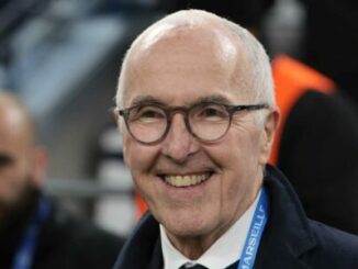 Homme âgé souriant avec lunettes dans un stade