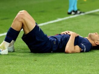 Footballeur allongé sur la pelouse du terrain