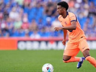 Footballeur en maillot orange courant avec ballon