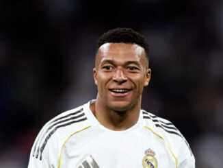 Footballeur souriant en maillot blanc sur le terrain