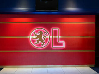 Logo OL lumineux sur mur rouge