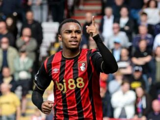 Footballeur en maillot rouge et noir levant le doigt