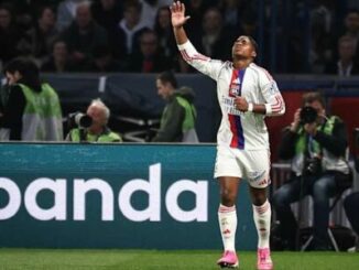 Footballeur en maillot blanc levant la main