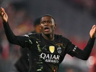 Footballeur en maillot noir levant les bras
