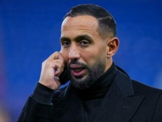 Homme barbu en manteau noir au téléphone